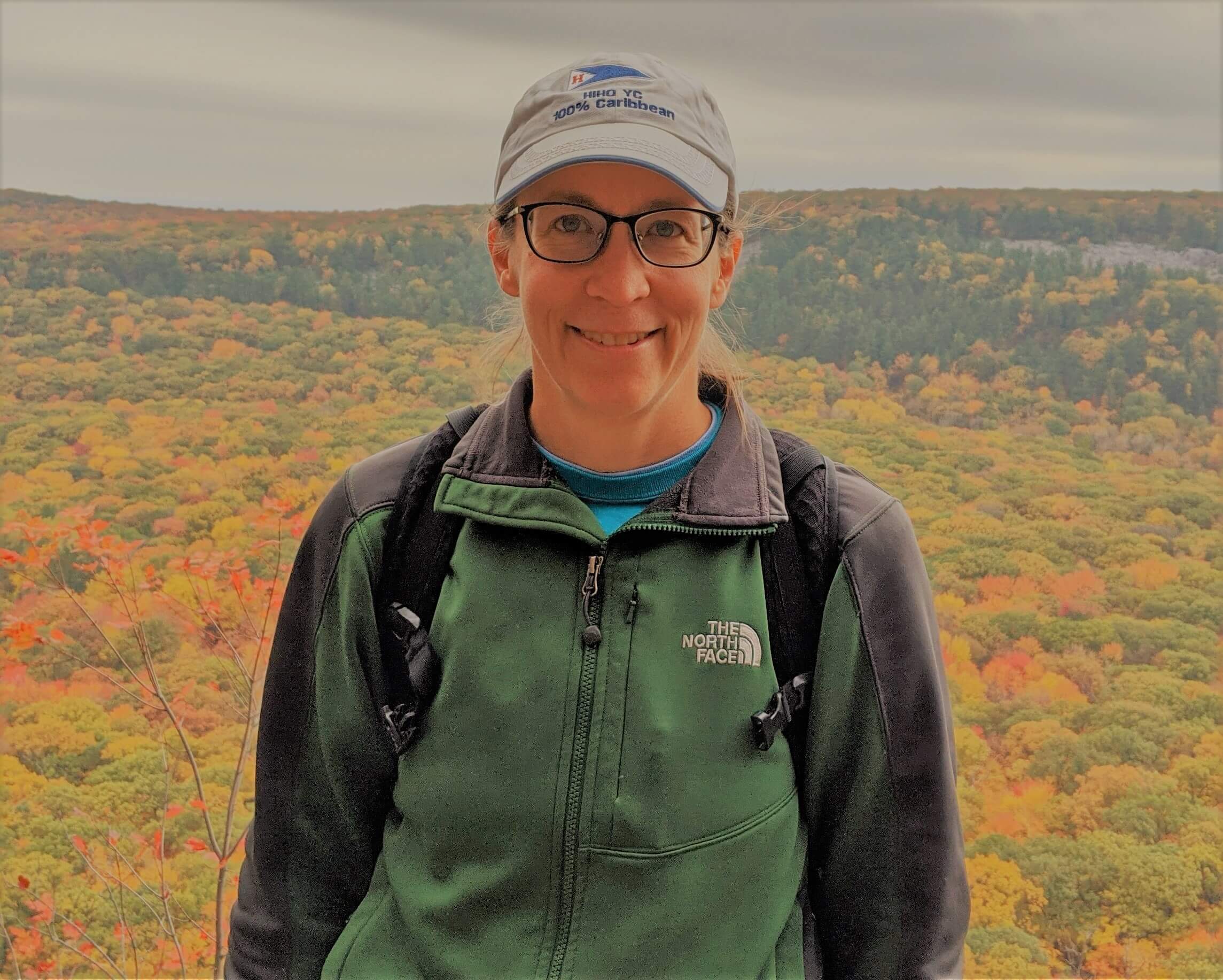 photo of Laura DeCicco with backdrop of treetops in autumn leaf colors