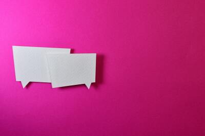 Two paper message balloons on a pink background